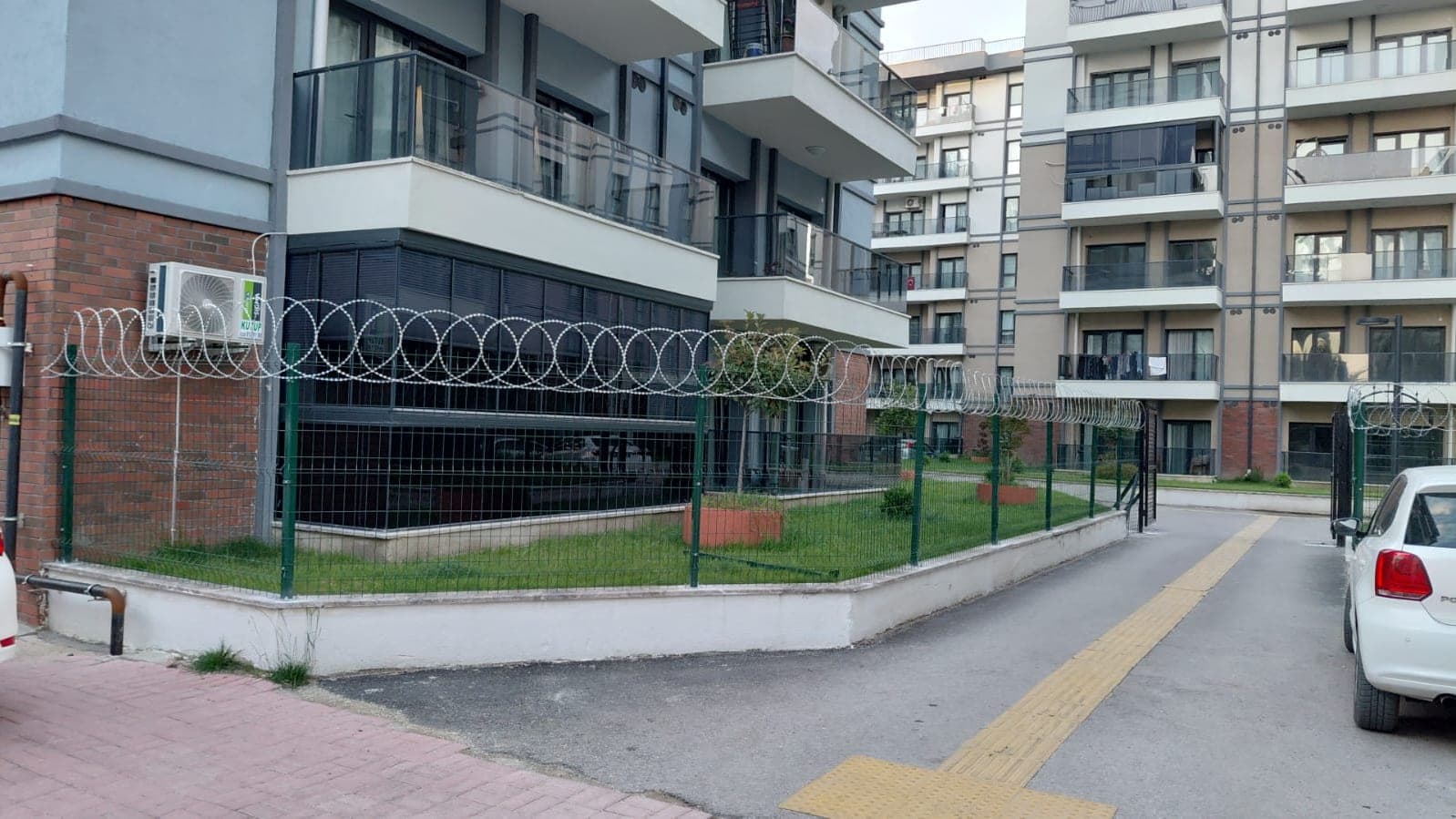 Apartman çevresinde üstüne jiletli tel çekilmiş panel çit
